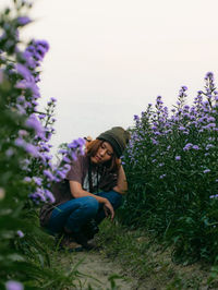 Full length of woman sitting on purple flowering plants