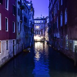 Canal amidst buildings in city at night