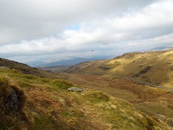 Scenic view of green landscape against cloudy sky