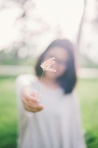Close-up of girl holding flower in field