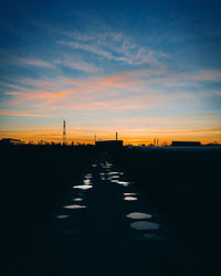 Silhouette city against sky during sunset