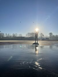 Man standing in frozen lake against sky during winter