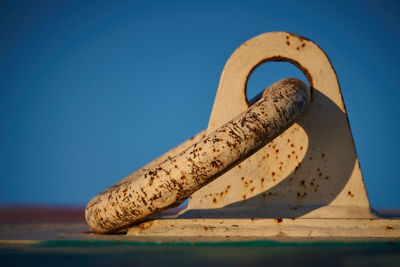 Close-up of rusty metal on wood against clear blue sky