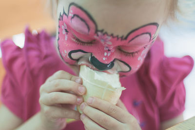 Close-up of girl with painted face eating ice cream
