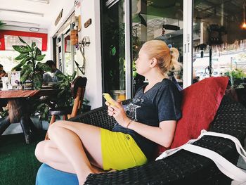 Woman using smart phone while sitting on chair in cafe