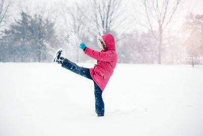 Girl kicking snow on land