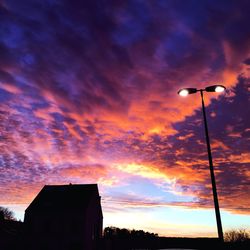 Low angle view of silhouette house against dramatic sky