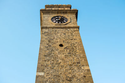 Low angle view of clock tower against clear blue sky