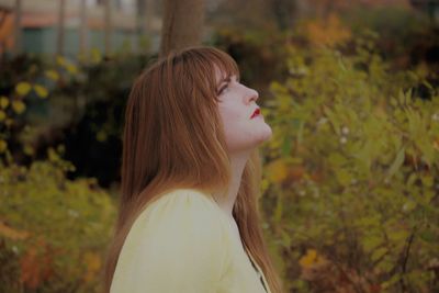 Young woman looking away against plants