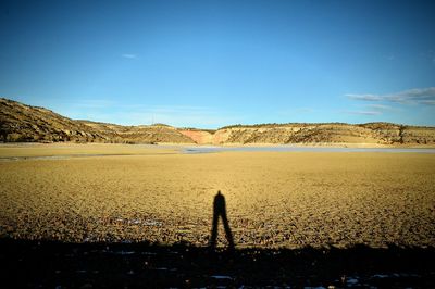 Long human shadow on dry lake bed