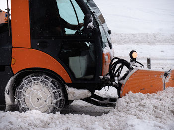 Road vehicle snowplow in action on whitewashed roads during a snowy day.