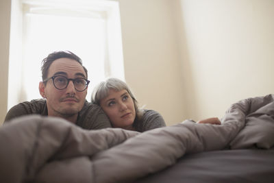 Young couple lying on bed watching tv