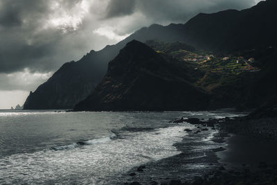 Light falling on houses from a cloudy sky with a beach in the foreground