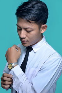 Close-up of businessman dressing against turquoise background