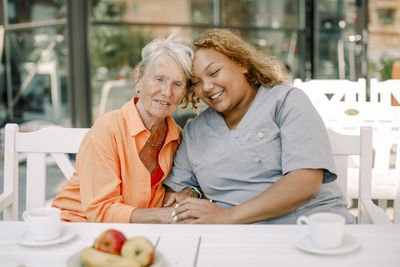 Elderly woman sitting with young female nurse at retirement home