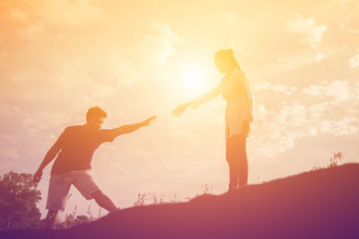 Low angle view of silhouette people standing against sky during sunset