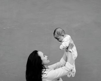Mother and daughter against white wall