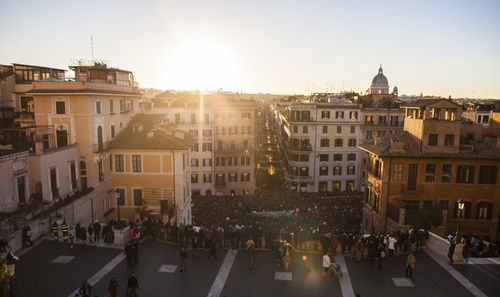 People on street amidst buildings in city against sky