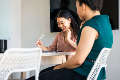 Smiling businesswoman sitting with colleague at table in board room