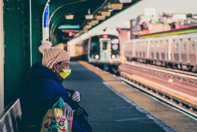 Rear view of woman standing on train at railroad station