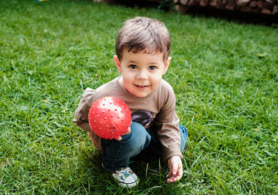 Super cute young boy is playing with a ball in the backyard