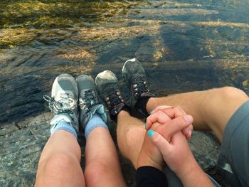 Low section of couple sitting on mountain