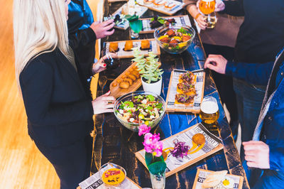 Midsection of friends with various food at table in restaurant