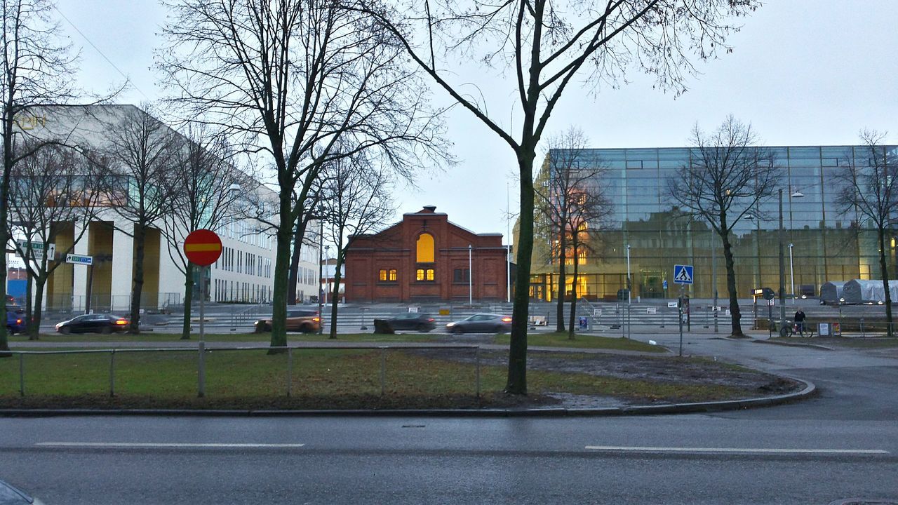 transportation, building exterior, architecture, built structure, land vehicle, mode of transport, car, bare tree, street, road, city, tree, clear sky, street light, city street, incidental people, sky, road marking, city life, day