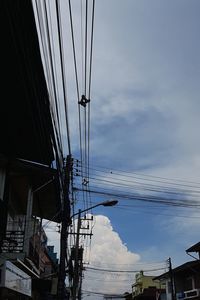 Low angle view of electricity pylon and buildings against sky