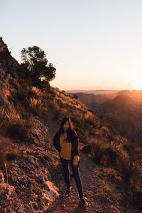 Portrait of woman standing on mountain against sky during sunset