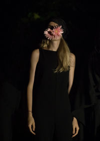 Woman holding flowers while standing against fabric