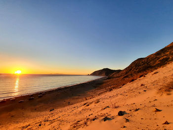 Scenic view of beach against clear sky during golden sunset at the beach