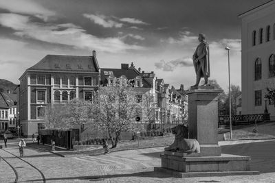 Statue in city against cloudy sky