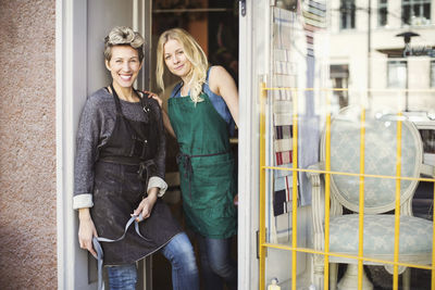 Portrait of confident fashion designers at studio doorway