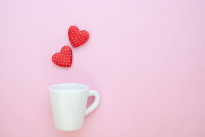 Close-up of heart shape over coffee against pink background