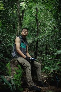 Portrait of young man sitting in forest