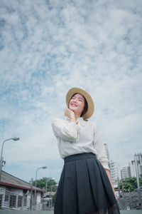 Smiling woman with eyes closed standing against sky