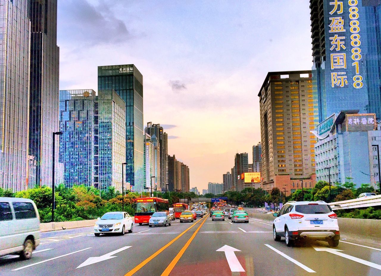 car, transportation, building exterior, land vehicle, architecture, city, built structure, road, street, mode of transport, road marking, sky, traffic, city life, skyscraper, city street, the way forward, office building, modern, on the move