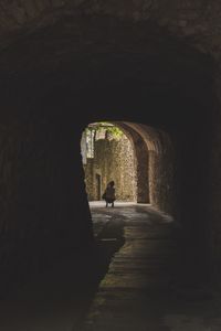 Rear view of woman crouching in tunnel