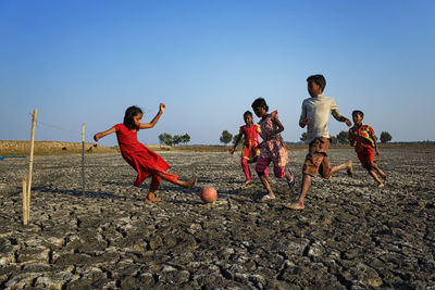 Children playing on field against clear sky