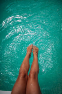 Low section of woman relaxing in swimming pool