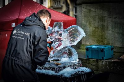 Midsection of man holding ice while standing in kitchen