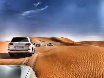 Cars on road in desert against sky