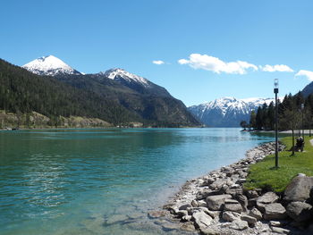 Scenic view of lake by snowcapped mountains against sky