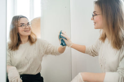 Positive woman cleaning glass at home