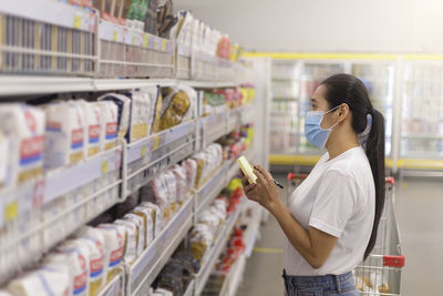 Side view of young woman standing in supermarket