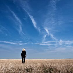 Rear view of man standing on field against sky