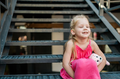 Portrait of cute girl sitting on railing