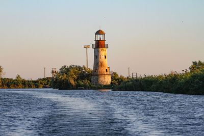 Lighthouse by lake against clear sky