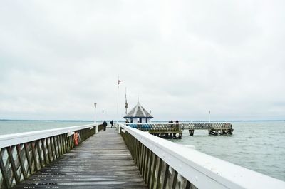 Pier on sea against cloudy sky